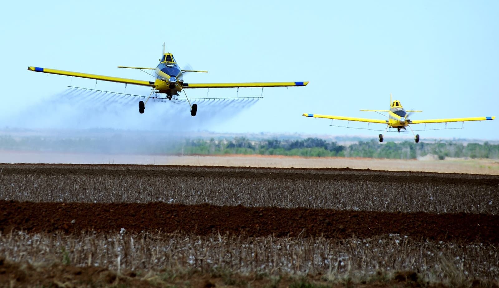 Two crop-dusting planes spraying a field in Oklahoma